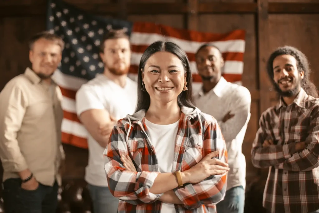 A diverse group of American patriots standing against the background of an American flag.