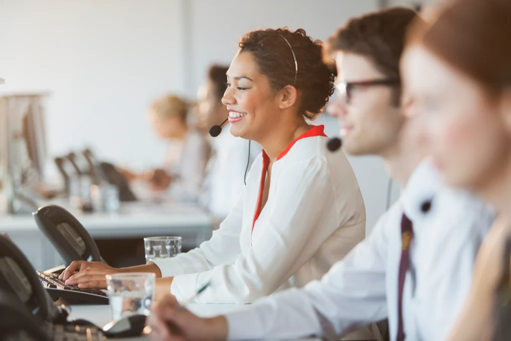 A smiling woman with a headset in a call center.