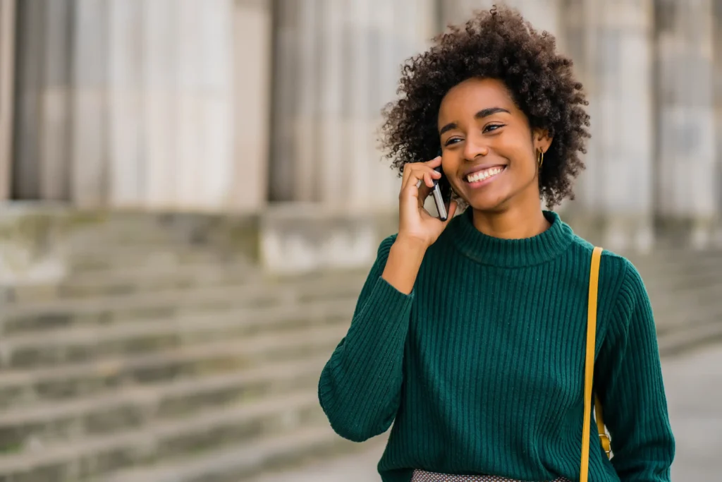 A smiling woman on the phone outside.